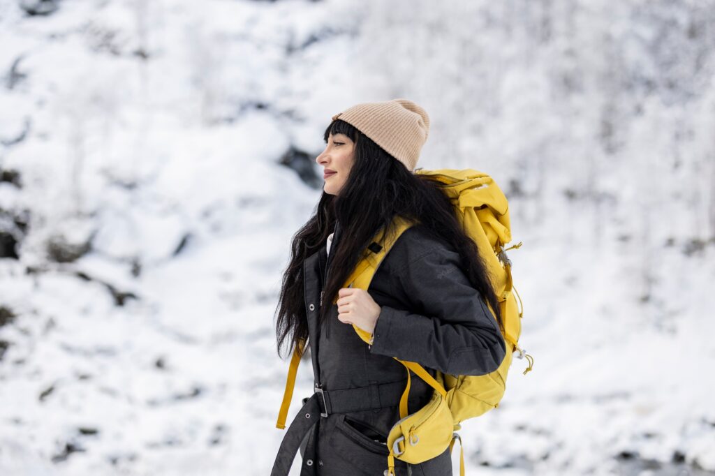 Adventurous Woman with Yellow Backpack Hiking in Snow